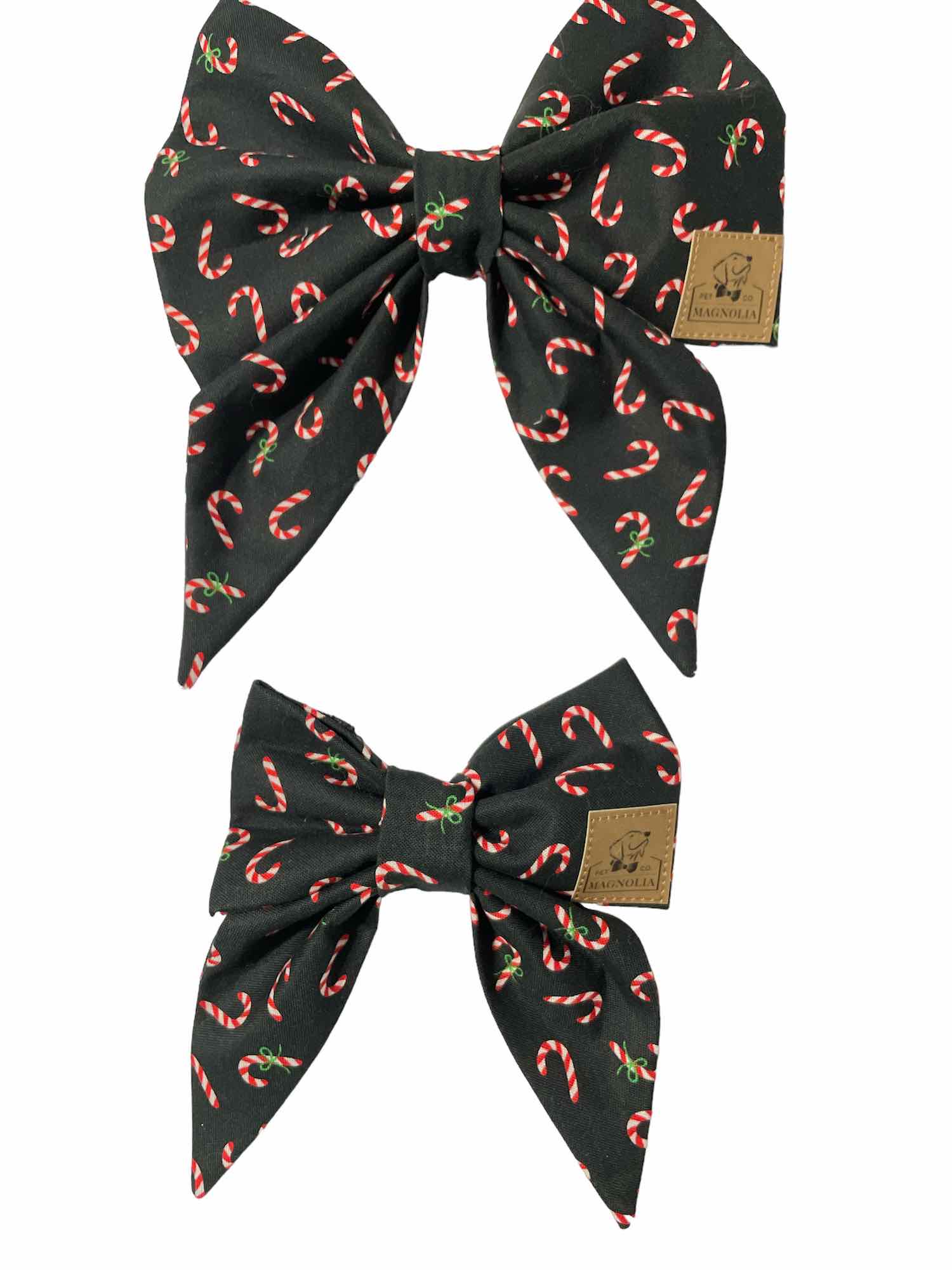 This stylish dog bow features sleek black fabric adorned with classic red and white candy canes