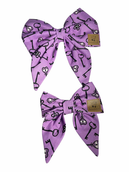 Dog bow made from vibrant purple fabric featuring a unique skeleton eye key pattern that glows in the dark, this bow is perfect for adding a touch of spooky fun to your furry friend's wardrobe