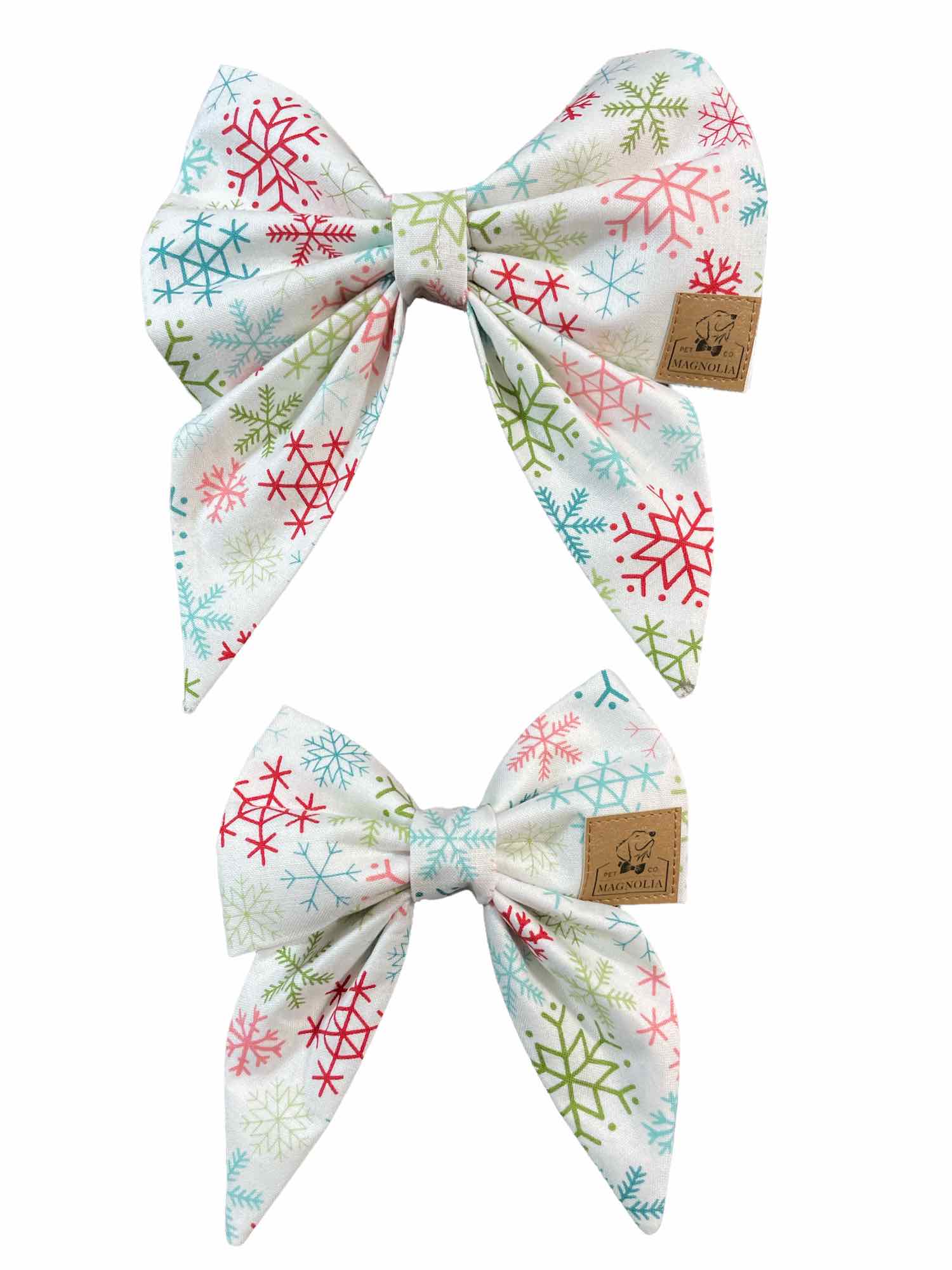 This enchanting accessory features pristine white fabric adorned with delicate snowflakes in light pink, blue, and green